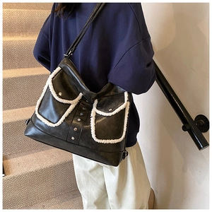 Detail of black faux leather tote bag featuring white faux fur trim and silver buckles