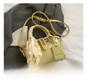 Detail of yellow patchwork tote bag with scarf-wrapped handle and leather brand tag