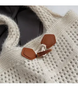 Close-up of cable knit tote bag featuring a vintage resin horn button and brown leather trim