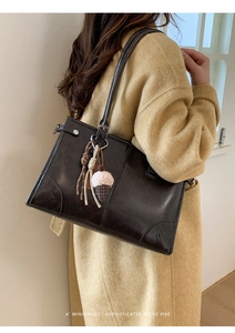Détail d'un sac à bandoulière rétro marron foncé avec pendentif pomme de pin décoratif