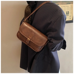 Close-up of vintage brown leather crossbody bag with metal buckle and textured finish