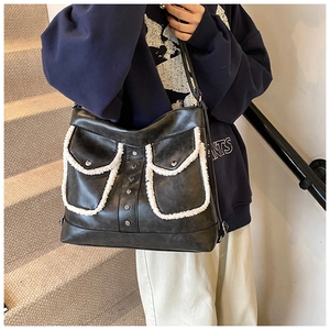 Detail of black leather tote bag with white plush trim and silver stud accents
