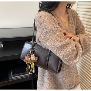 Détail d'un sac bandoulière carré marron foncé avec breloque ours et étoile mignon