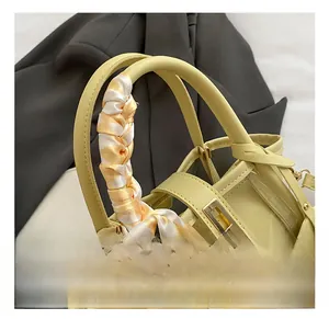 Detail of yellow handbag handle wrapped in plaid scarf with gold twist lock closure