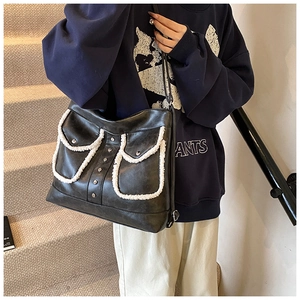Detail of black matte leather shoulder bag with white fleece trim and metal rivet pockets