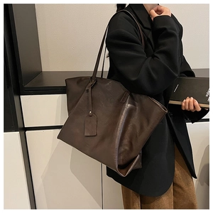 Detailed view of deep brown matte leather tote bag worn over the shoulder for commute