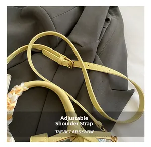 Detail of yellow bucket bag featuring adjustable shoulder strap and silk scarf handle