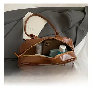 Spacious interior of vintage brown leather underarm bag with mobile phone and cosmetics
