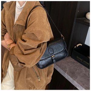 Detail of vintage black textured leather underarm bag with flap closure and buckle