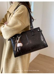 Détail d'un sac cabas rétro en cuir marron avec un charmant pendentif en peluche
