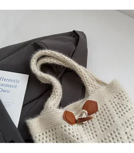 Detail of hollow knit tote bag featuring a toggle button and brown leather patch