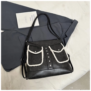 Detail of black faux leather tote bag with white plush trim and silver rivets