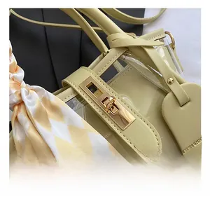 Detail view of transparent yellow bucket bag with golden twist lock and plaid scarf