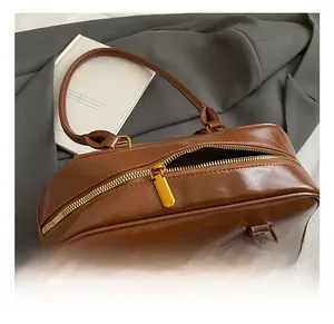 Close-up of premium golden metal zipper detail on brown glossy leather shoulder bag