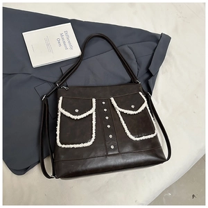 Detailed close-up of dark coffee shoulder bag with fleece trim and silver rivet accents