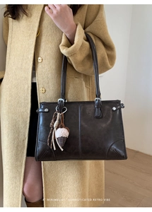 Détail d'un sac cabas rétro marron foncé avec boucles argentées et pendentif peluche