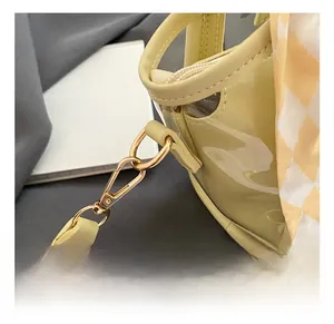 Close-up of golden metal hook on yellow PVC bucket bag with plaid ribbon decoration