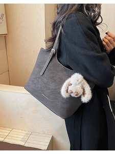 Close-up of charcoal gray tote bag with matte texture and plush bunny charm detail