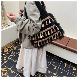 Detail of bohemian black knit tote bag with gold trim and multi-color fringe tassels