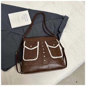 Close-up of brown leather bag with plush trim pockets and silver stud detailing