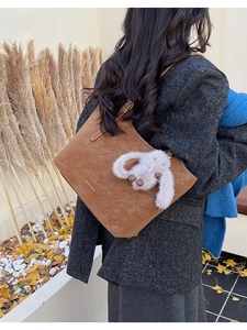 Brown leather tote bag with rabbit charm detail and fashion text on autumn background