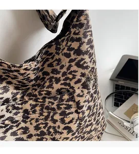 Detailed texture of leopard print tote bag with laptop and accessories on office desk