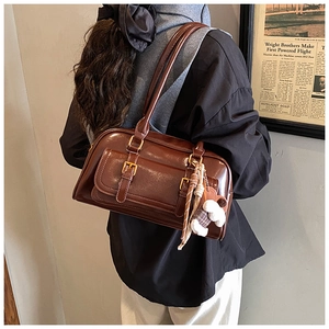 Detail of vintage brown leather underarm bag with plush bear charm and metallic buckles