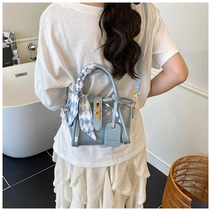 Detail of light blue transparent PVC bucket bag with scarf handle and gold twist lock