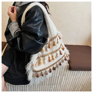 Detail of bohemian tote bag featuring multi-color tassels and golden chain accents