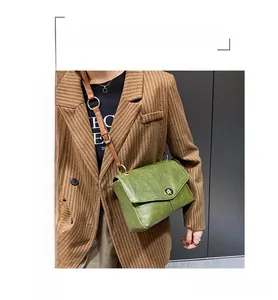 Détail du sac messager vintage vert avec fermoir bronze et bandoulière marron