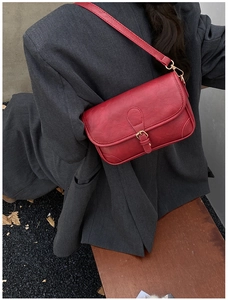 Detail of red vintage PU leather bag with lychee texture and golden hardware accents