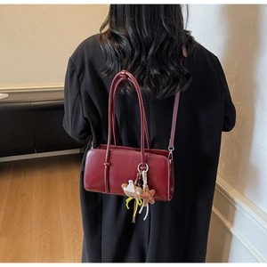 Détail du sac carré en cuir bordeaux avec breloque ours et bandoulière amovible