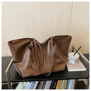 Detail of tan large capacity tote bag in textured soft faux leather on a shelf