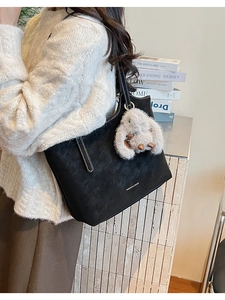 Detail of black matte tote bag with contrast stitching and plush rabbit charm