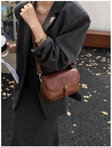 Detail of vintage brown leather-textured crossbody bag styled with a grey autumn suit