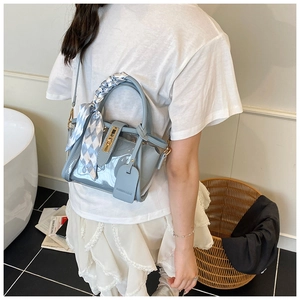 Detail of light blue transparent PVC bucket bag with silk scarf and gold lock buckle