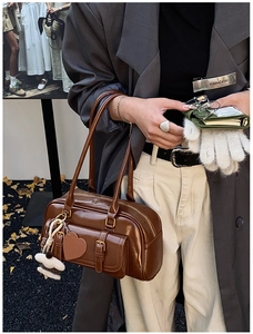 Detailed view of brown retro underarm bag with decorative charms and heart tag