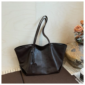 Detail of a dark coffee large faux leather tote bag with slim shoulder straps and tag