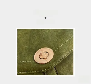 Détail macro du sac en cuir vintage vert foncé avec fermoir rotatif ovale doré et couture