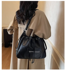 Detail of black quilted leather tote bag with drawstring closure worn by model