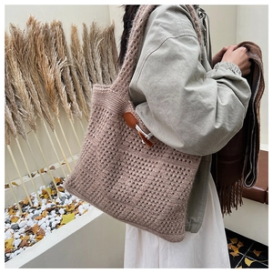 Detailed knit texture of large hollow tote bag with stylish leather horn buckle closure