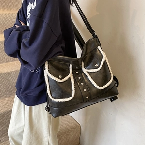 Black leather shoulder tote bag with white faux shearling pockets and silver rivet studs