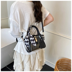 Detailed view of a black transparent PVC bucket bag with silk scarf on a female model