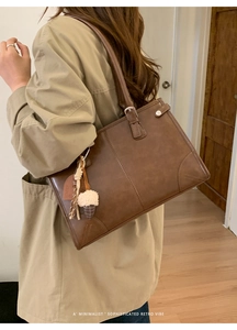 Détail d'un sac cabas rétro marron avec bandoulière réglable et breloque en forme de cœur