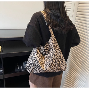 Detailed back view of a large leopard print hobo tote bag worn by a model