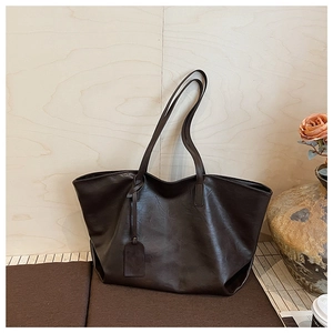 Close-up of deep brown tote bag with premium leather texture and long shoulder strap