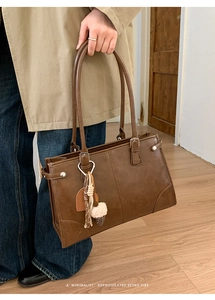 Gros plan du sac porté épaule rétro marron avec pompon et breloque en peluche