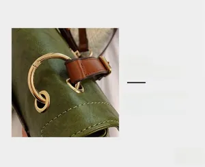 Vue détaillée de la garniture en métal doré et des coutures du sac messager en cuir vert foncé