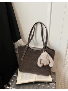 Detail of dark brown matte tote bag with plush rabbit charm and fashion logo print