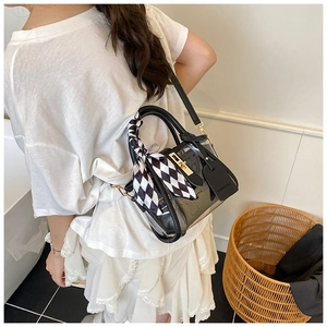 Detail of transparent PVC bucket bag with black leather trim and silk scarf on handle